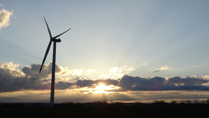 Electrical windmill at sunset generates renewable energy