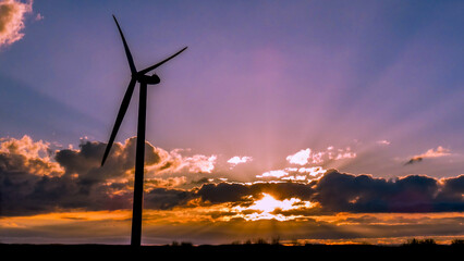 Electrical windmill at colorful sunset generates renewable energy