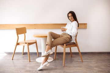 Positive young woman with happy face sitting at the cafe indoors.