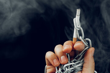 Male hand in metal chains holding cigarette