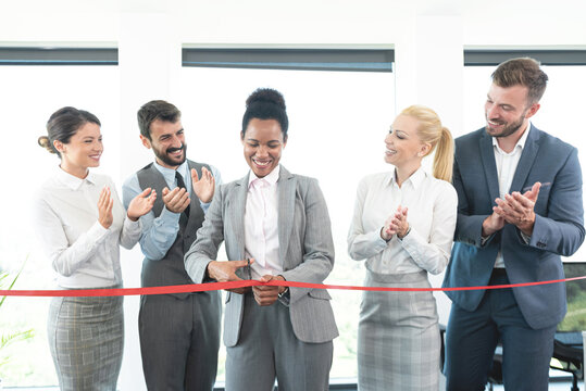 Successful business people cutting red ribbon at office