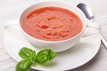 Gazpacho in a white plate and basil