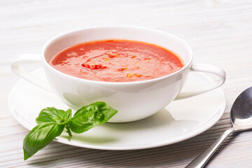 Gazpacho in a white plate and basil