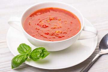 Gazpacho in a white plate and basil