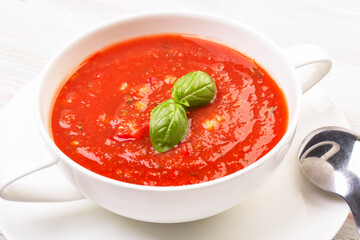Gazpacho in a white plate and basil