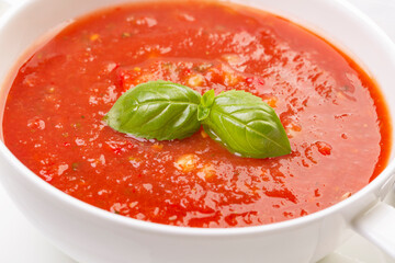 Gazpacho in a white plate and basil