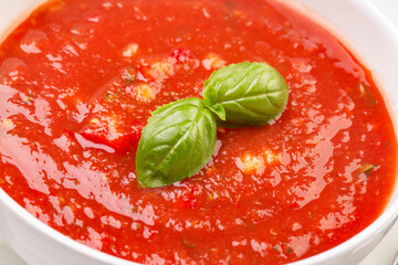 Gazpacho in a white plate and basil