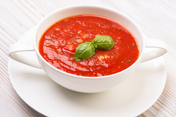 Gazpacho in a white plate and basil