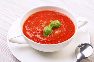 Gazpacho in a white plate and basil