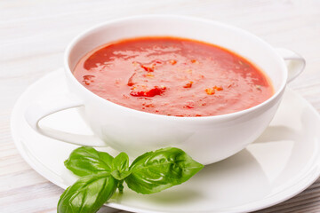 Gazpacho in a white plate and basil