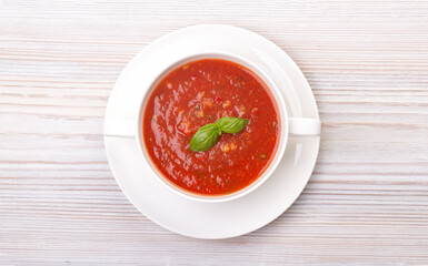 Gazpacho in a white plate and basil