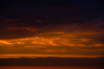Obraz premium Heavy cloudy sky at sunset. Orange line of light between black clouds. A landscape of beautiful nature