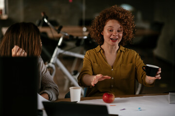Businesswomen drinking coffee in office.. Colleagues discussing work in office.