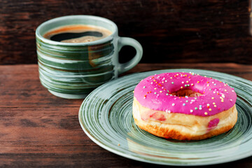 Glazed donut on green plate with cup of coffee
