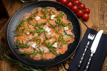 Salmon carpaccio with cheese and arugula
