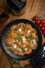 Salmon carpaccio with cheese and arugula
