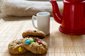 colorful chocolate chip cookies with red coffee pot and white mug