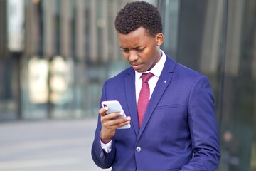 Sad concentrated upset frustrated black African Afro American man looking at screen of his smartphone. Unhappy office worker, businessman in formal suit outdoors. Problems with cell mobile phone. 
