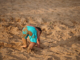 Fototapeta na wymiar Chłopiec bawiący się w piasku