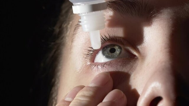 Close-up shooting of young woman using eye drops