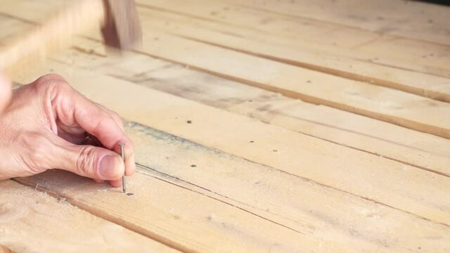 hands driving a nail with a hammer
