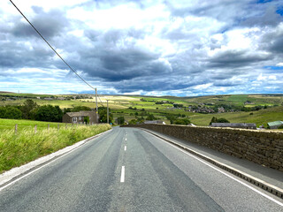 Looking along, Rochdale Road, with stone walls, fields, and distant hills near, Denshaw, Oldham, UK