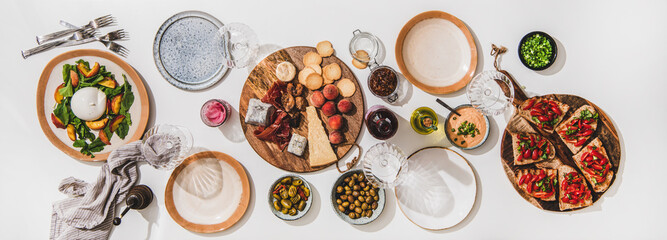Family wine and snack party. Flay-lay of wineglases, boards with cheese, fruit, smoked meat, tomato...