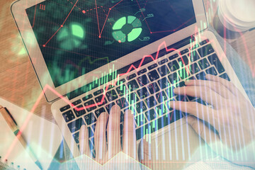 Double exposure of man's hands typing over computer keyboard and forex graph hologram drawing. Top view. Financial markets concept.