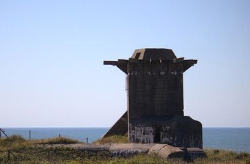 Militärischer Bunkerturm an der Küste vor blauem Himmel