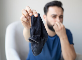 man smell sock with athlete foot problem and he feel stinky in the room