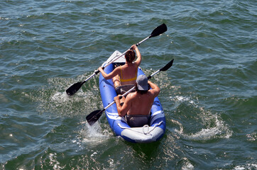 Overhead view of a young couple paddling an inflatable canoe.