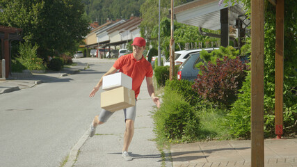 Delivery guy kicks packages in someone's driveway on a sunny day in the suburbs.