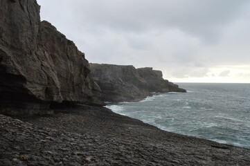 Fototapeta na wymiar Oceanic huge rocky cliffs with a cloudy sky