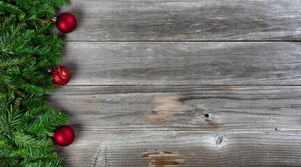 Fototapeta na wymiar Merry Christmas and Happy New Year theme consisting of fir branches and red ball ornaments on left side of rustic wooden boards
