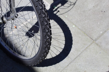 Roda de bicileta com a sombra em uma calçada