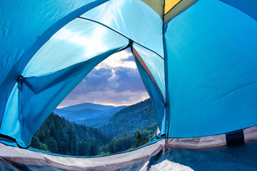 Photo of early morning mountains valley view from a blue camping tent door.