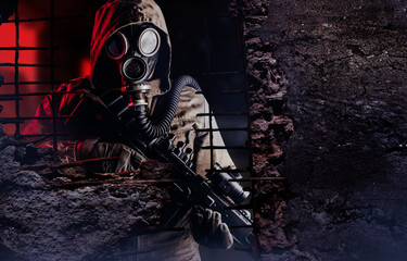 Photo of a post apocalyptic stalker soldier in gas mask and rifle looking through destructed...