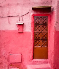 Old metal door and a mailbox  on an old, dameged pink wall, one colour