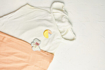 Top view of white top with brooch and pink skirt on white concrete background. Brooch made of...