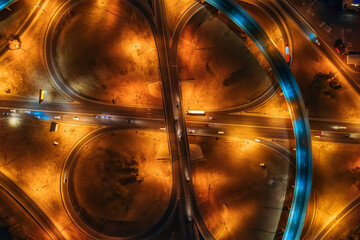 Large roundabout or road transport junction at night with car traffic, aerial top view.