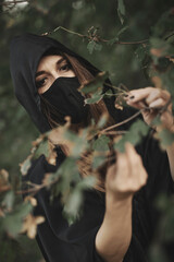 Witch picking herbs for her brews and potions in the woods