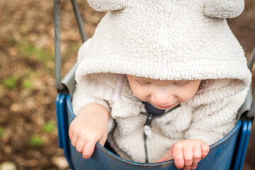 baby looking down on a swing with hooded sweater