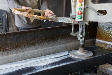 Man polishes granite blanks on a polishing machine.