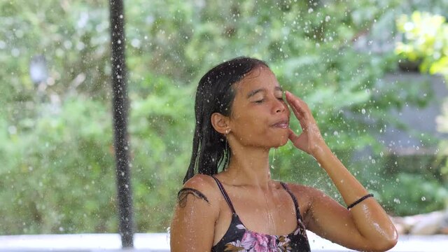 Close up portrait of happy beautiful young woman taking shower outdoor.