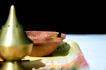 Clay diya candle illuminated in Dipavali, Hindu festival of lights. Traditional oil lamp on dark background