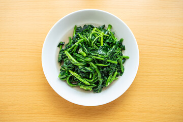 A dish of watercress on a wooden table