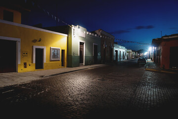 Traditional domnestic Mexican street with colonial buildings and flags in the night, Merida, Yucatan, Mexico