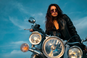 Fototapeta na wymiar Attractive, sexy brunette posing on motorcycle, blue sky background 