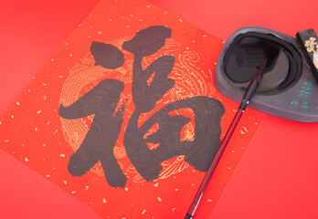 Chinese inkstone and writing brush on red background