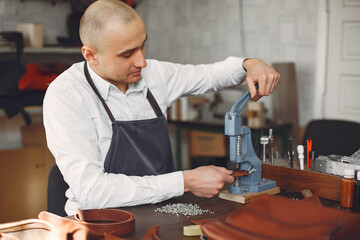 Man working with leather. Professional makes a holes. Man use device for holes.